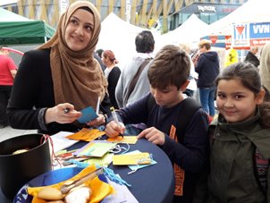 Mutter mit Kindern am Stand beim Zettel ausfüllen